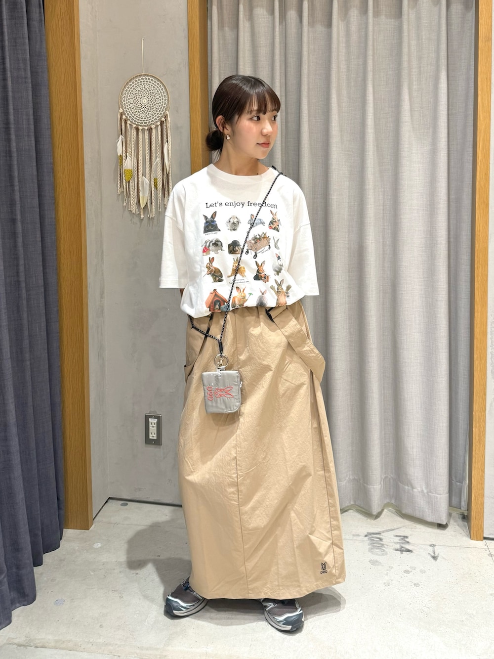 ホワイト系のTシャツ/カットソー、ベージュ系のスカート、グレー系のスマホグッズを着用したレディースの春コーディネートの2枚目の写真