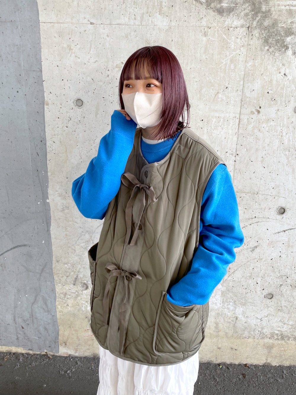 グリーン系のベスト、ホワイト系のスカート、ホワイト系のスニーカーを着用したレディースの冬コーディネートの4枚目の写真