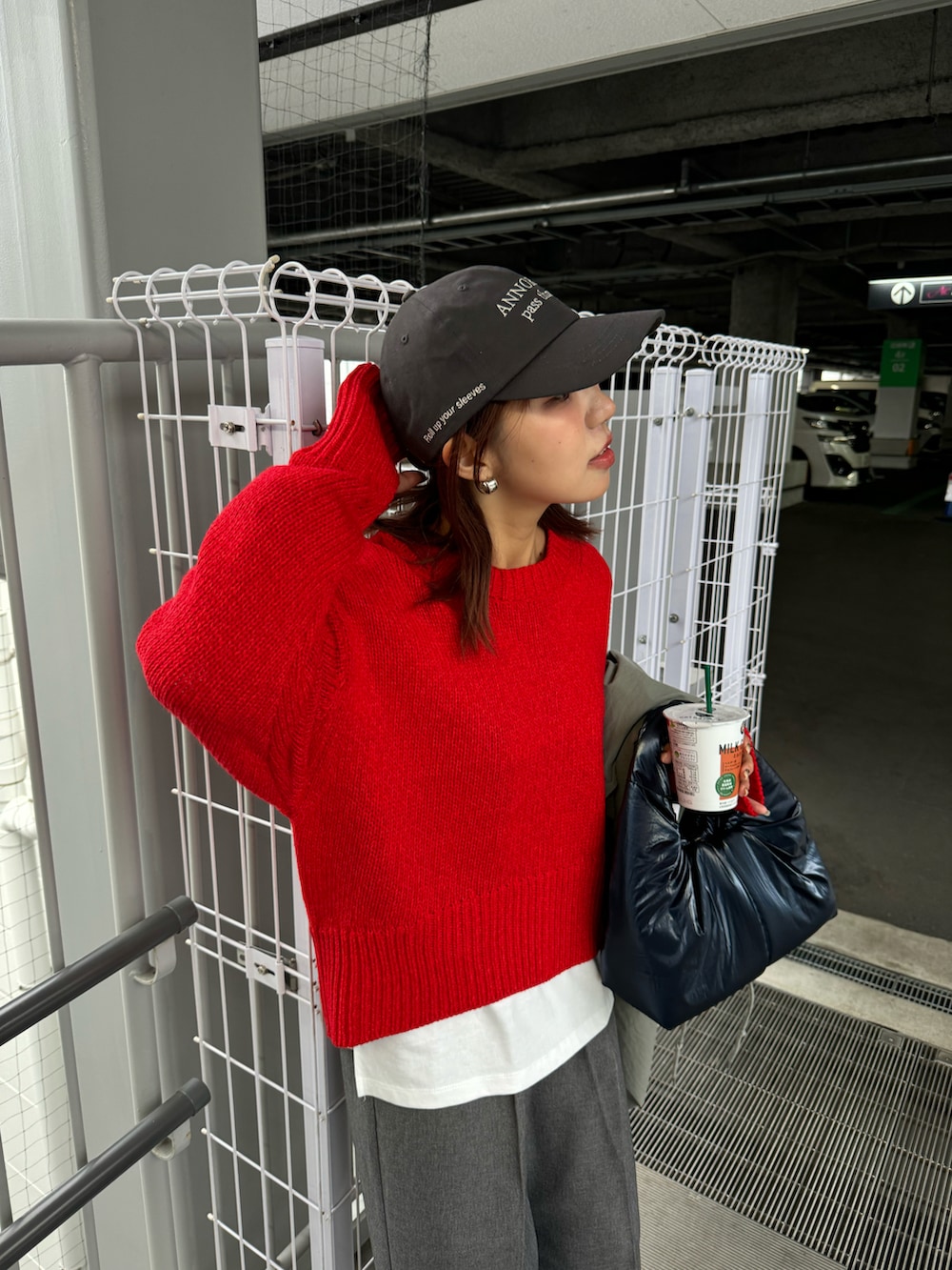 レッド系のニット/セーター、ブルー系のトートバッグ、グレー系のスラックスを着用したレディースの冬コーディネートの3枚目の写真