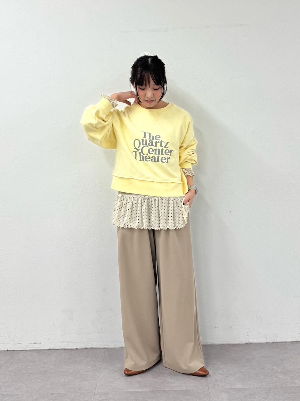 イエロー系のスウェット、ホワイト系のTシャツ/カットソー、ベージュ系のスラックスを着用したレディースの春コーディネートの2枚目の写真