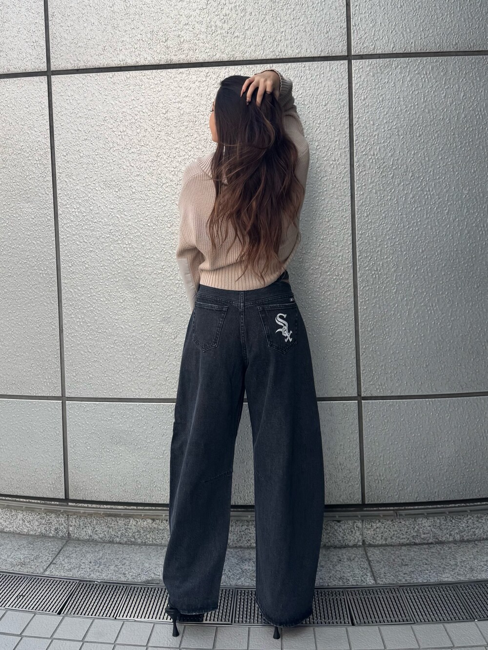 ブラック系のデニムパンツ、ベージュ系のニット/セーター、ブラック系のパンプスを着用したレディースの夏コーディネートの3枚目の写真