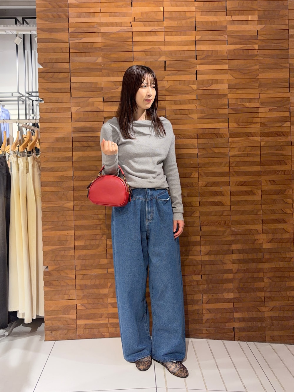 グレー系のニット/セーター、レッド系のショルダーバッグ、ブルー系のデニムパンツを着用したレディースの夏コーディネートの2枚目の写真