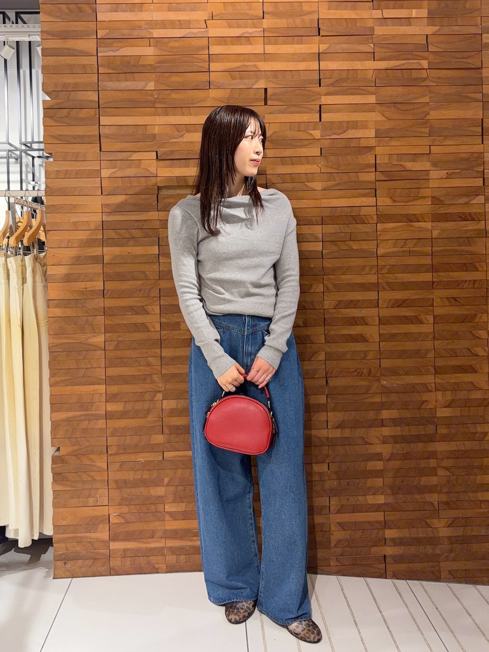 グレー系のニット/セーター、レッド系のショルダーバッグ、ブルー系のデニムパンツを着用したレディースの夏コーディネートの3枚目の写真
