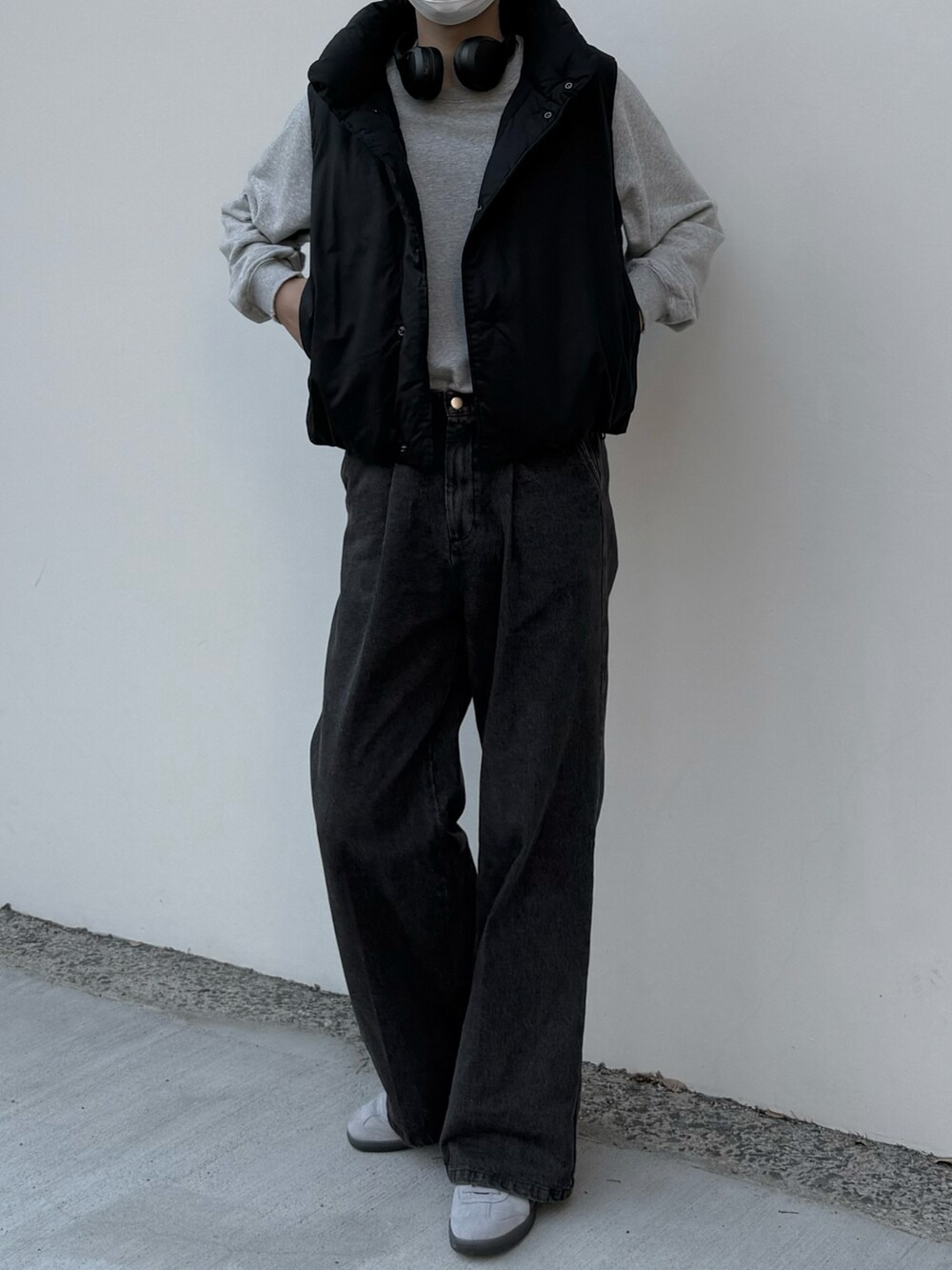 グレー系のデニムパンツ、グレー系のスウェット、ブラック系のダウンベストを着用したメンズの秋コーディネートの4枚目の写真