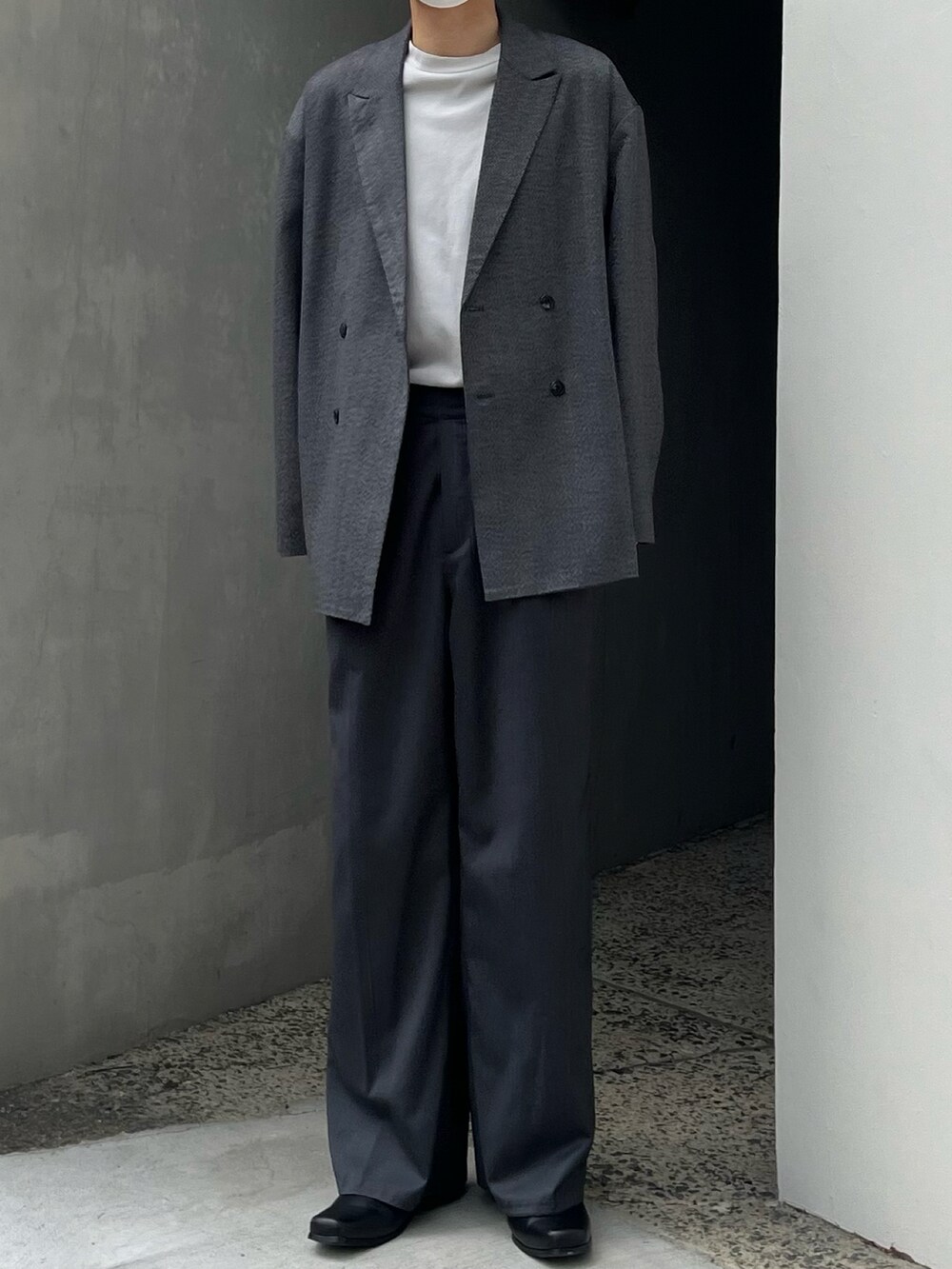 グレー系のスラックス、ブラック系のブーツ、グレー系のテーラードジャケットを着用したメンズの春コーディネートの2枚目の写真