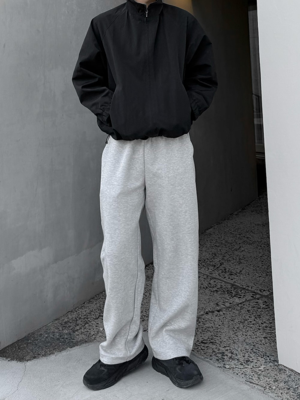 グレー系のスウェットパンツ、ブラック系のブルゾン、ブラック系のスニーカーを着用したメンズの春コーディネートの2枚目の写真