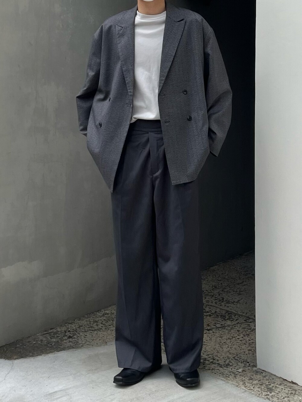 グレー系のスラックス、ブラック系のブーツ、グレー系のテーラードジャケットを着用したメンズの春コーディネートの3枚目の写真