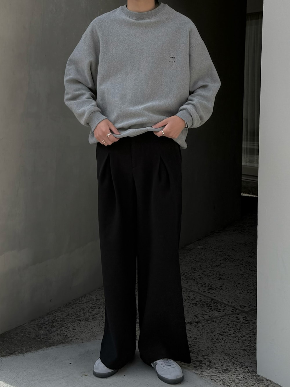 ブラック系のスラックス、グレー系のスニーカー、グレー系のスウェットを着用したメンズの秋コーディネートの4枚目の写真