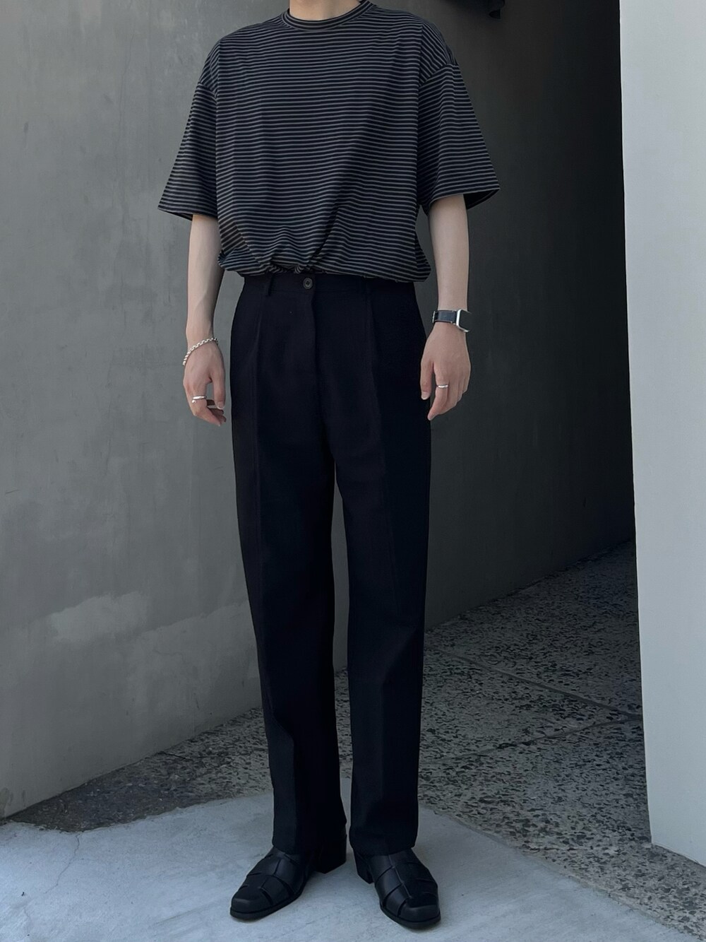 ブラック系のサンダル、ブラック系のスラックス、ブラック系のTシャツ/カットソーを着用したメンズの夏コーディネートの3枚目の写真