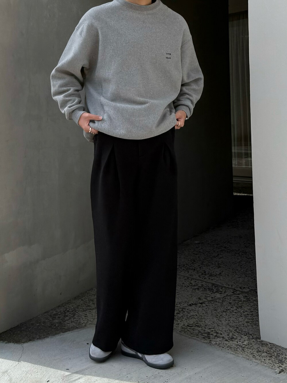ブラック系のスラックス、グレー系のスニーカー、グレー系のスウェットを着用したメンズの秋コーディネートの3枚目の写真