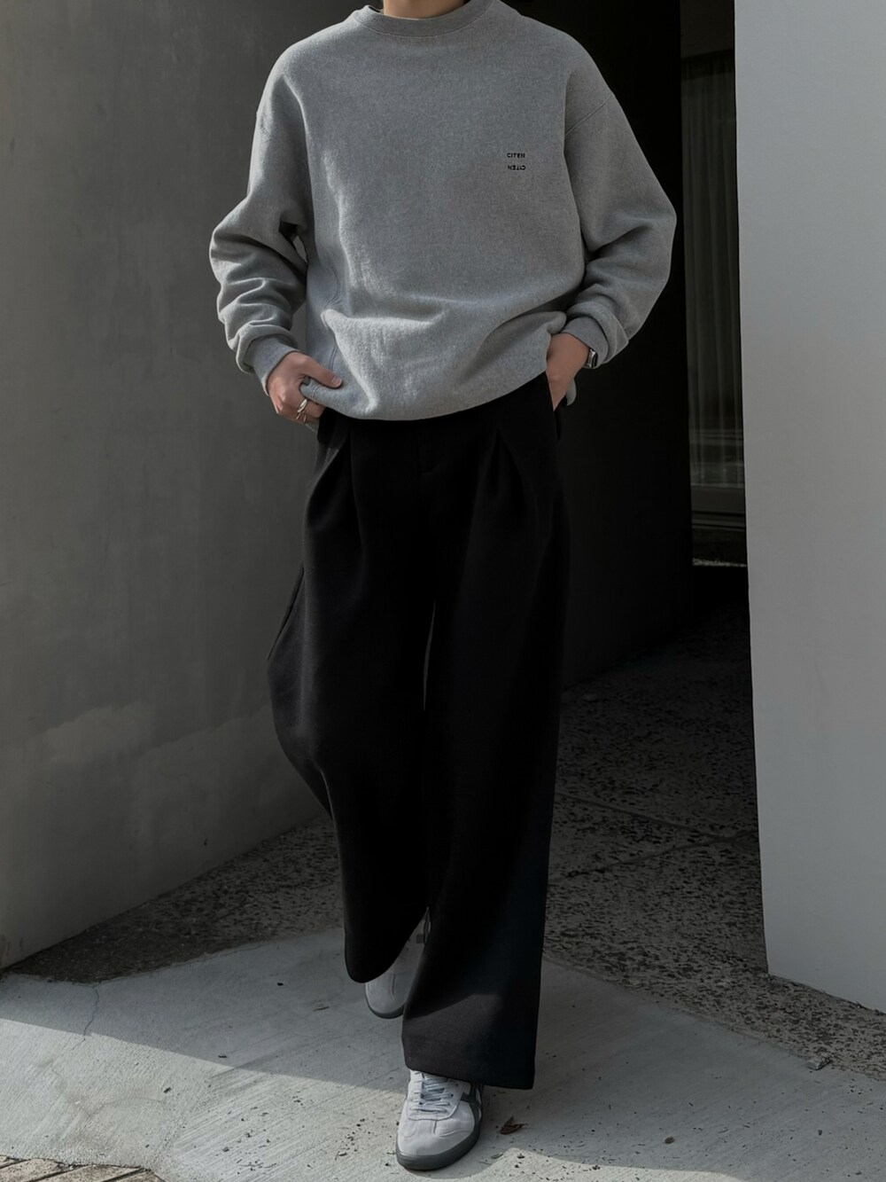ブラック系のスラックス、グレー系のスニーカー、グレー系のスウェットを着用したメンズの秋コーディネートの2枚目の写真