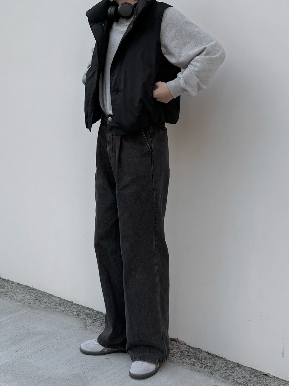 グレー系のデニムパンツ、グレー系のスウェット、ブラック系のダウンベストを着用したメンズの秋コーディネートの3枚目の写真