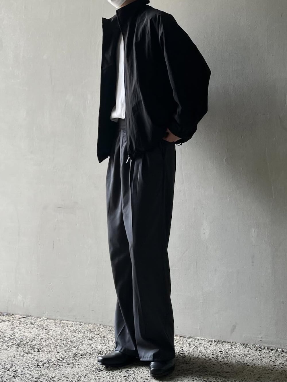 グレー系のTシャツ/カットソー、ブラック系のブルゾン、グレー系のスラックスを着用したメンズの春コーディネートの3枚目の写真