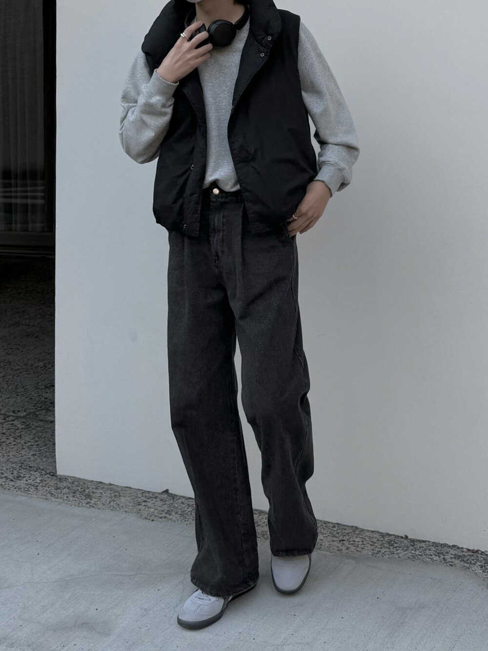 グレー系のデニムパンツ、グレー系のスウェット、ブラック系のダウンベストを着用したメンズの秋コーディネートの2枚目の写真