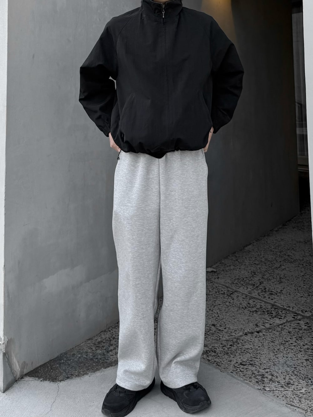 グレー系のスウェットパンツ、ブラック系のブルゾン、ブラック系のスニーカーを着用したメンズの春コーディネートの3枚目の写真