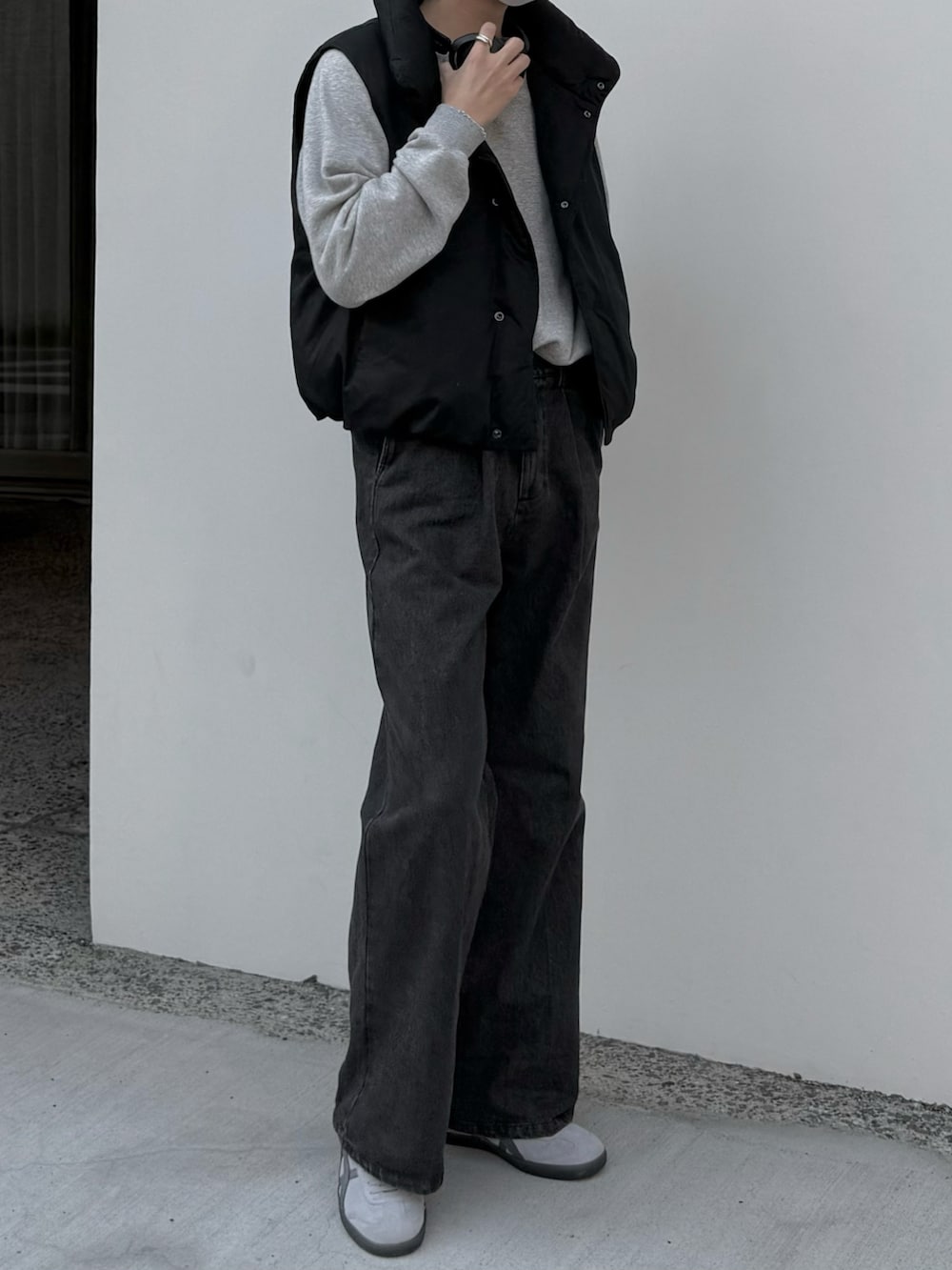 グレー系のデニムパンツ、グレー系のスウェット、ブラック系のダウンベストを着用したメンズの秋コーディネートの5枚目の写真