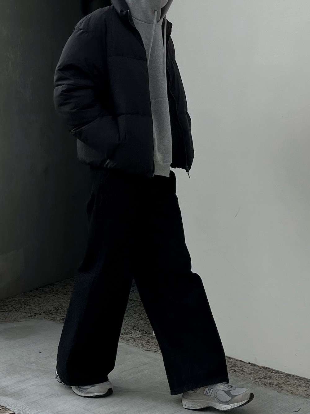 ブラック系のデニムパンツ、ブラック系のダウンジャケット/コート、グレー系のパーカーを着用したメンズの冬コーディネートの2枚目の写真