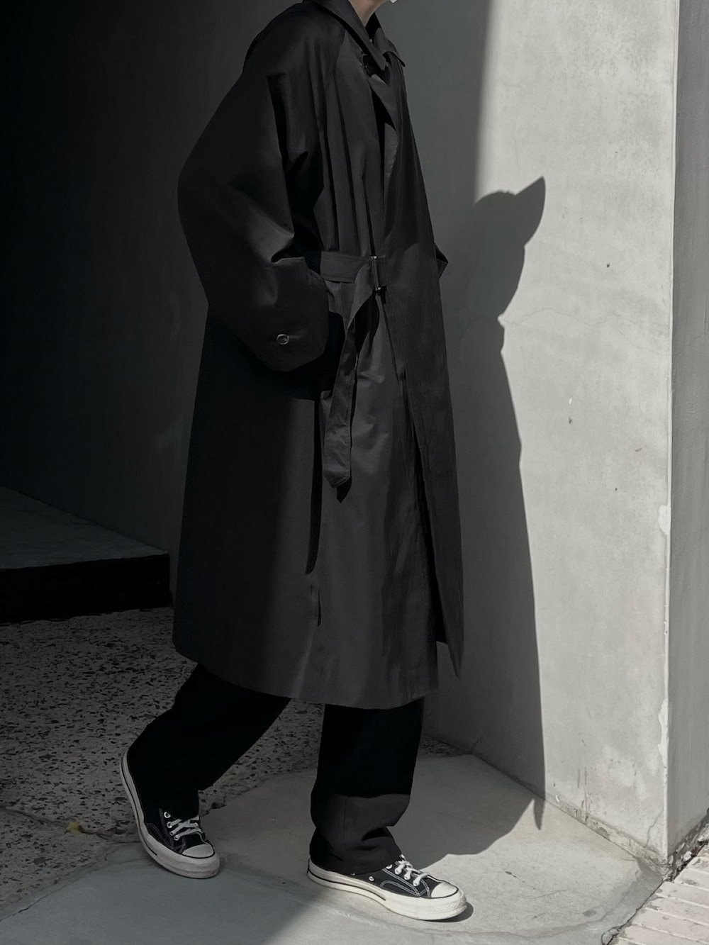 ブラック系のトレンチコート、ブラック系のスラックスを着用したメンズの春コーディネートの2枚目の写真