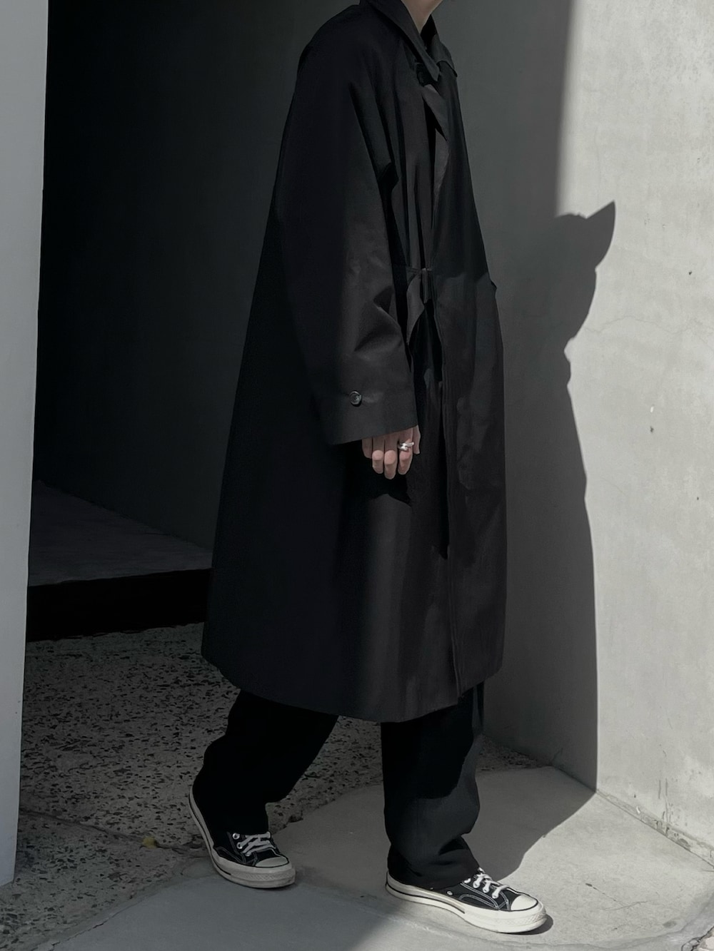 ブラック系のトレンチコート、ブラック系のスラックスを着用したメンズの春コーディネートの3枚目の写真