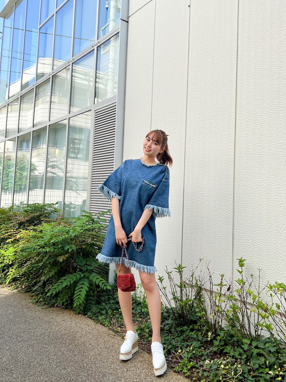 ホワイト系のスニーカー、ブルー系のワンピース、レッド系のショルダーバッグを着用したレディースの夏コーディネートの3枚目の写真