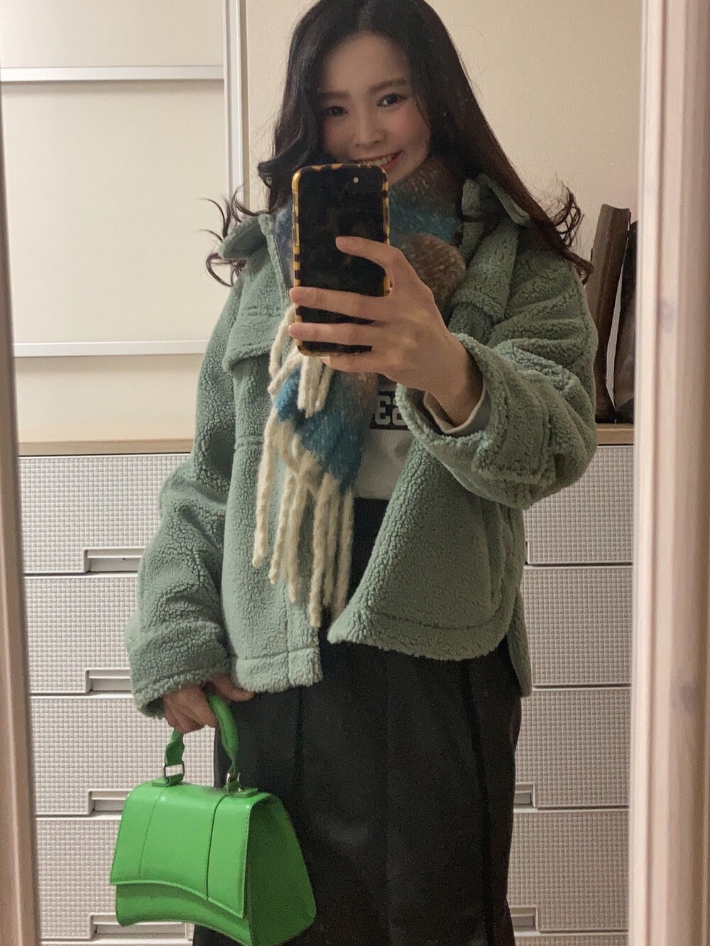 グリーン系のブルゾン、ブラック系のTシャツ/カットソー、グリーン系のショルダーバッグを着用したレディースの冬コーディネートの2枚目の写真