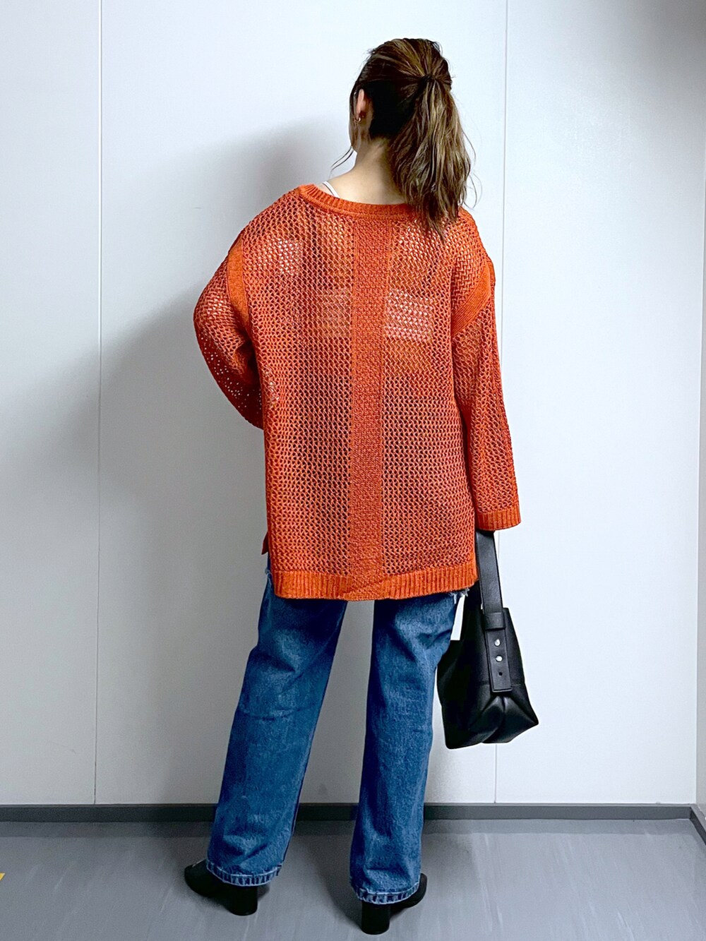 オレンジ系のニット/セーター、ホワイト系のキャミソール、ブラック系のショルダーバッグを着用したレディースの夏コーディネートの4枚目の写真