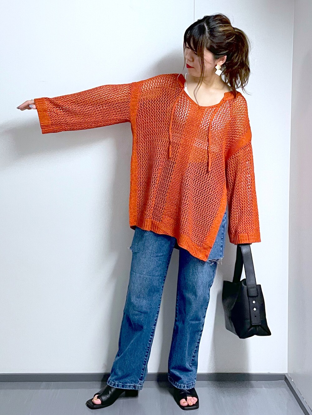 オレンジ系のニット/セーター、ホワイト系のキャミソール、ブラック系のショルダーバッグを着用したレディースの夏コーディネートの3枚目の写真