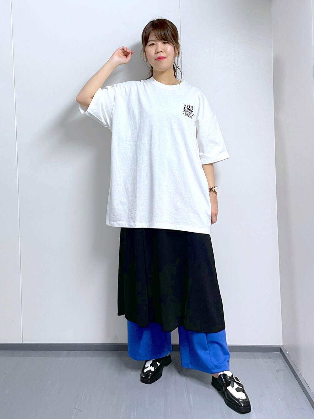 ブルー系のスラックス、ホワイト系のTシャツ/カットソー、ブラック系のワンピースを着用したレディースの春コーディネートの2枚目の写真