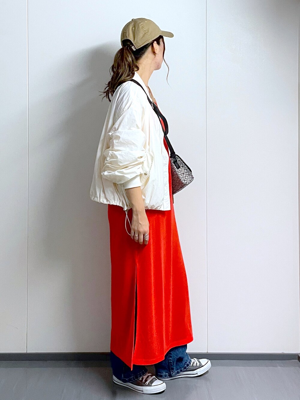 ホワイト系のMA-1、ブラック系のショルダーバッグ、オレンジ系のワンピースを着用したレディースの夏コーディネートの3枚目の写真