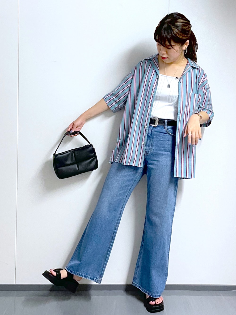 ブラック系のショルダーバッグ、ブルー系のデニムパンツ、ブラック系のサンダルを着用したレディースの夏コーディネートの2枚目の写真