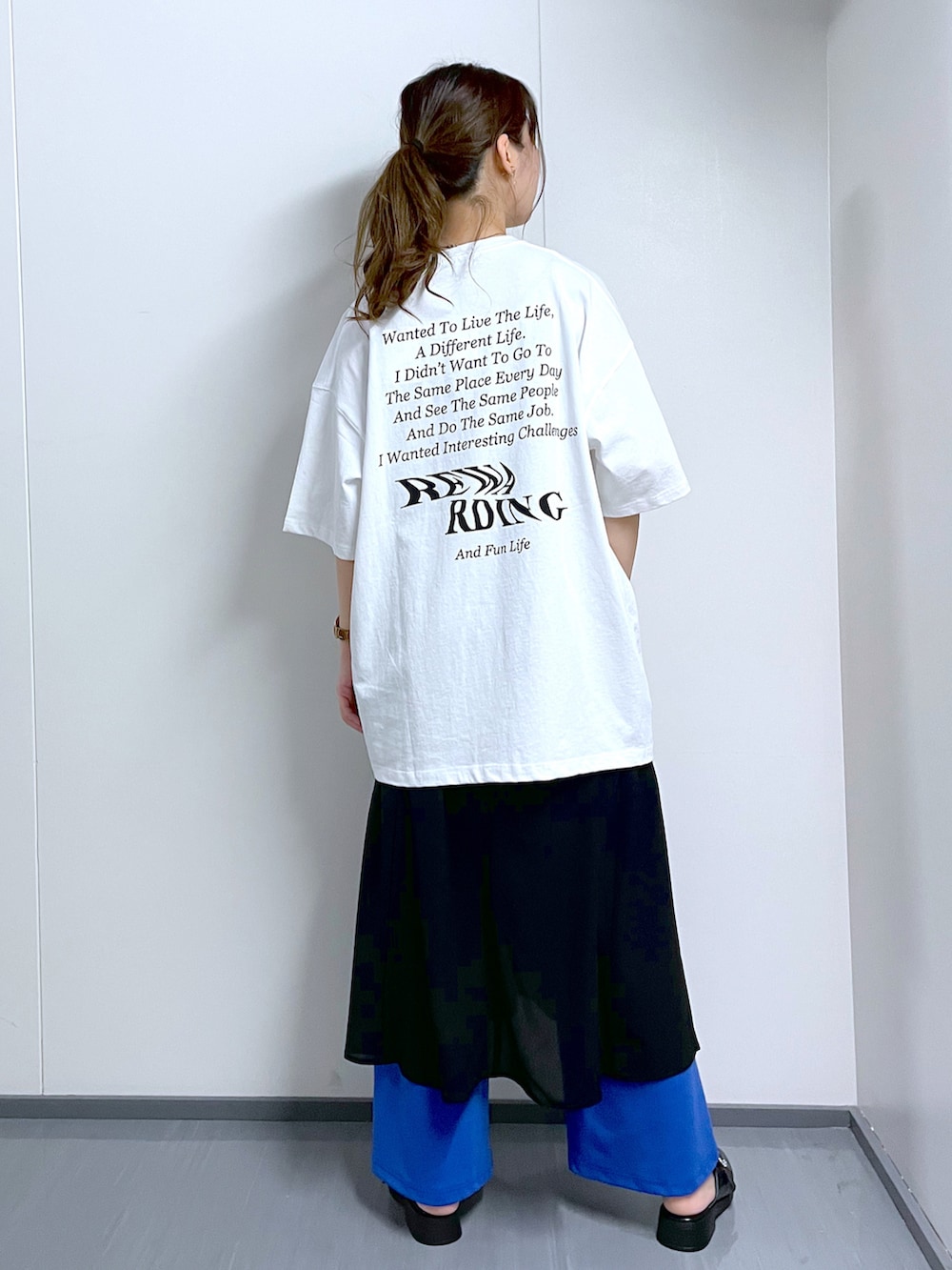 ブルー系のスラックス、ホワイト系のTシャツ/カットソー、ブラック系のワンピースを着用したレディースの春コーディネートの4枚目の写真