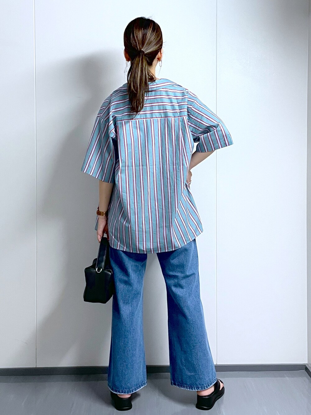 ブラック系のショルダーバッグ、ブルー系のデニムパンツ、ブラック系のサンダルを着用したレディースの夏コーディネートの4枚目の写真