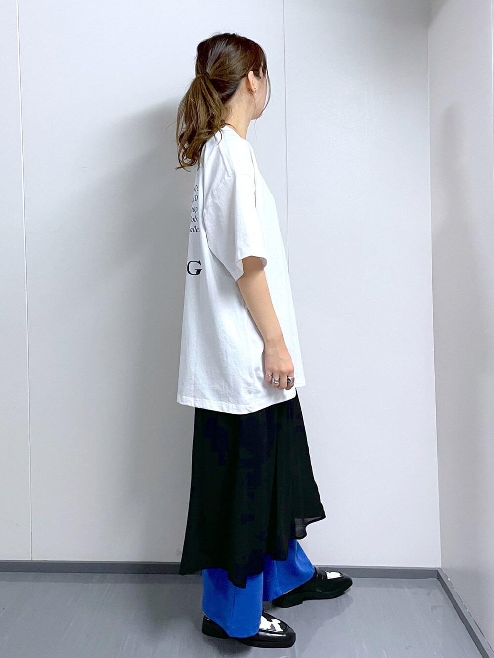 ブルー系のスラックス、ホワイト系のTシャツ/カットソー、ブラック系のワンピースを着用したレディースの春コーディネートの3枚目の写真