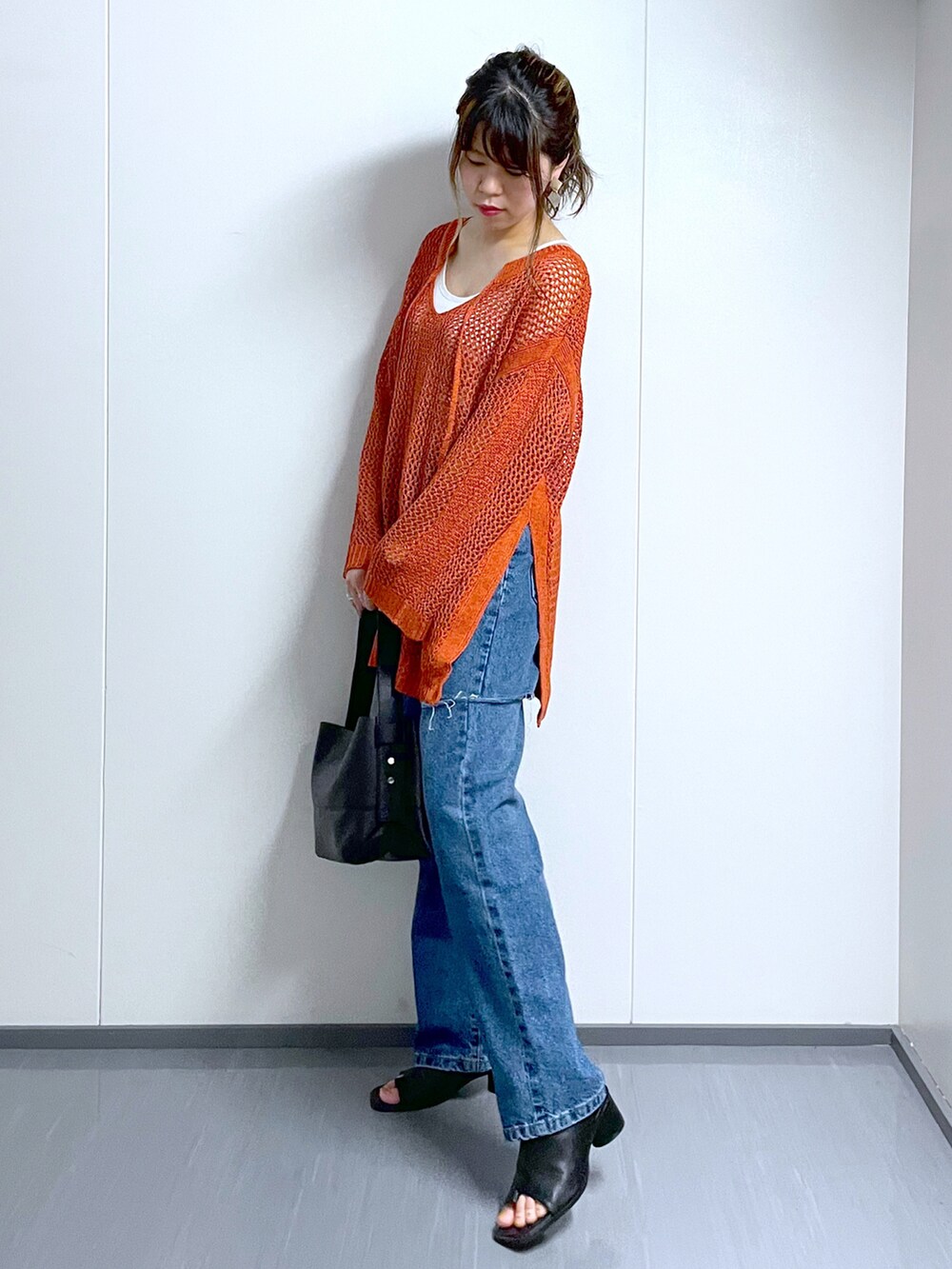 オレンジ系のニット/セーター、ホワイト系のキャミソール、ブラック系のショルダーバッグを着用したレディースの夏コーディネートの2枚目の写真
