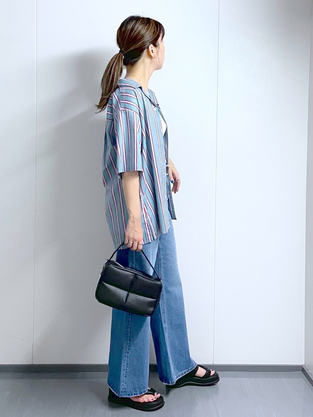 ブラック系のショルダーバッグ、ブルー系のデニムパンツ、ブラック系のサンダルを着用したレディースの夏コーディネートの3枚目の写真
