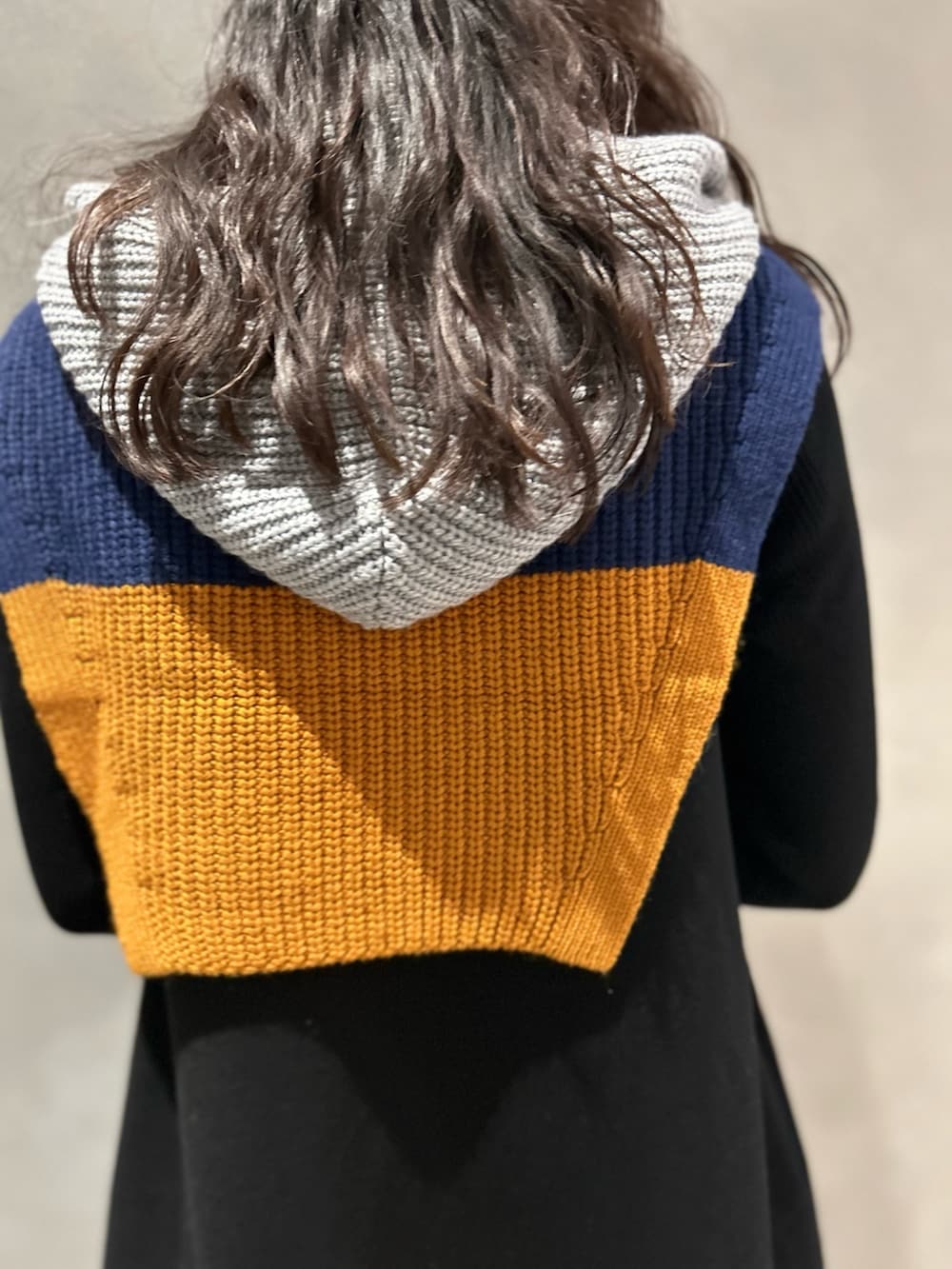 ブラック系のワンピース、ブラック系のブーツ、グレー系のネックウォーマー/スヌードを着用したレディースの冬コーディネートの7枚目の写真