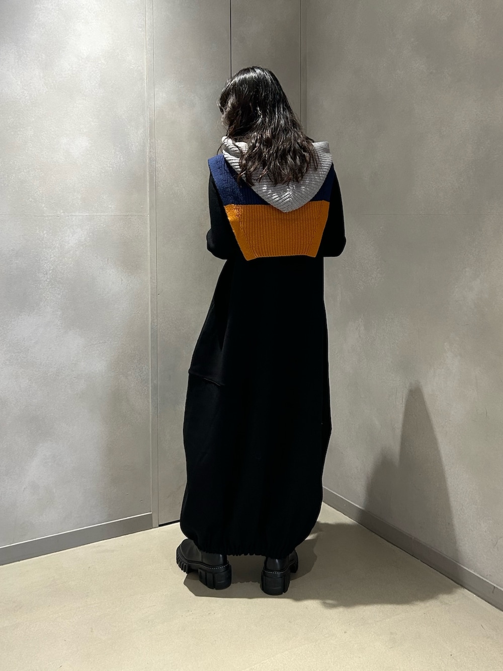 ブラック系のワンピース、ブラック系のブーツ、グレー系のネックウォーマー/スヌードを着用したレディースの冬コーディネートの2枚目の写真