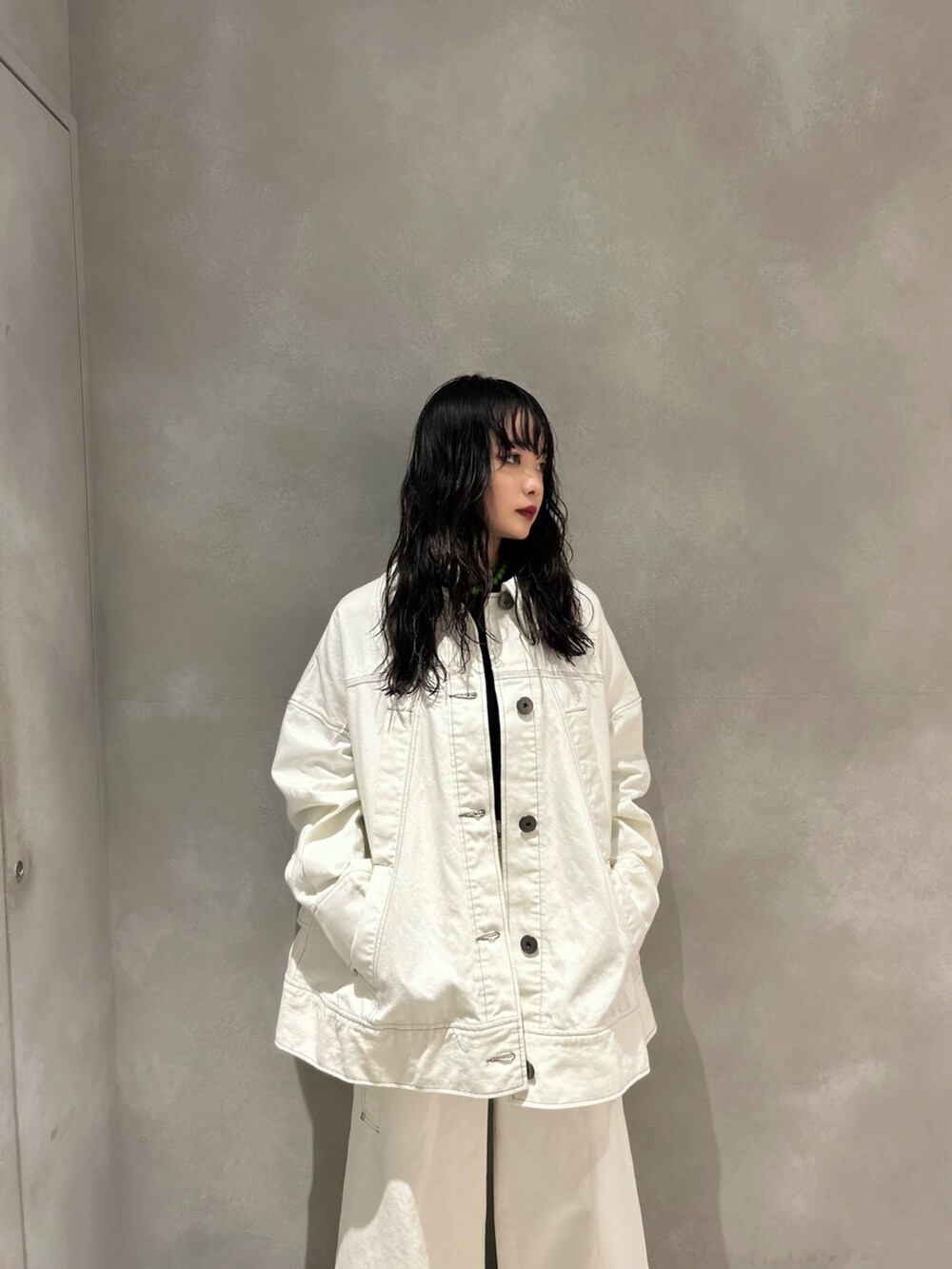 ホワイト系のデニムパンツ、ホワイト系のデニムジャケット、ブラック系のニット/セーターを着用したレディースの春コーディネートの3枚目の写真