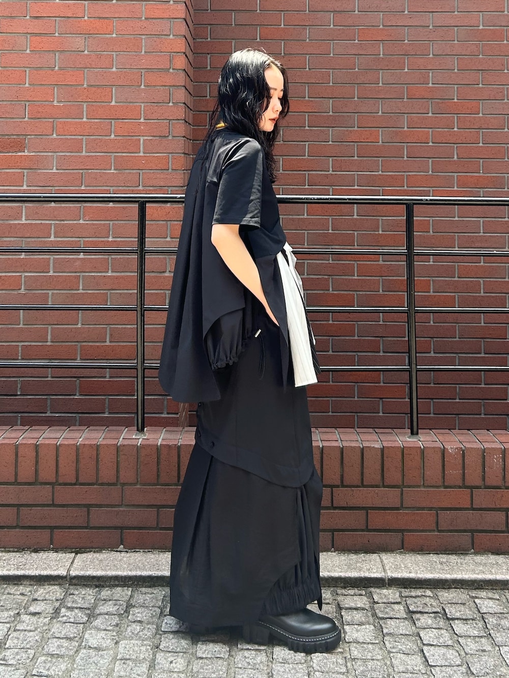 ブラック系のスカート、ブラック系のTシャツ/カットソー、ブラック系のブーツを着用したレディースの夏コーディネートの2枚目の写真