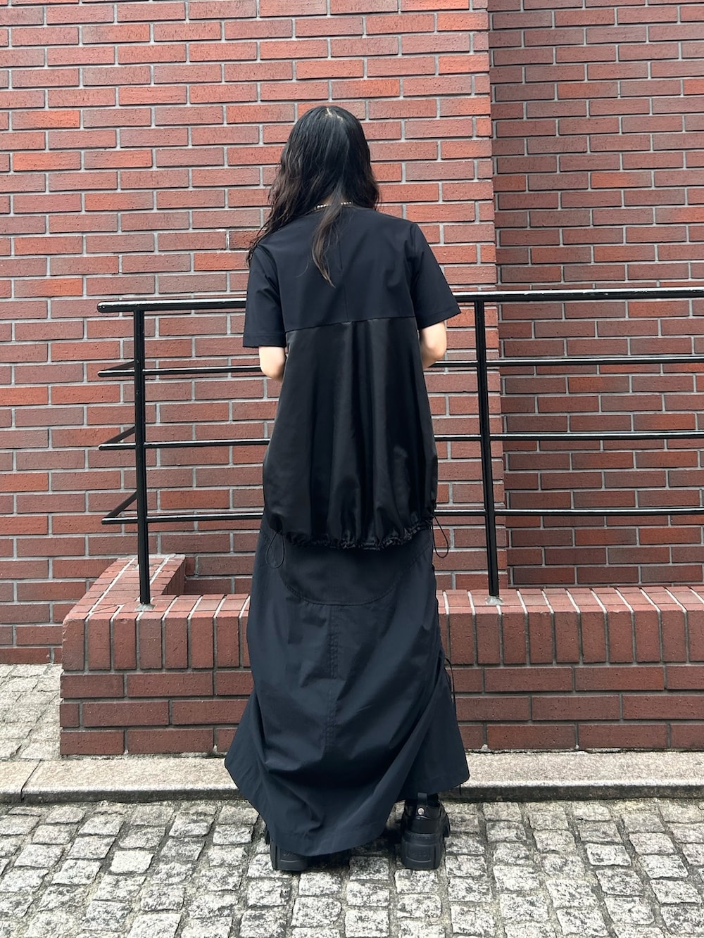 ブラック系のTシャツ/カットソー、ブラック系のスカート、ブラック系のローファーを着用したレディースの秋コーディネートの4枚目の写真