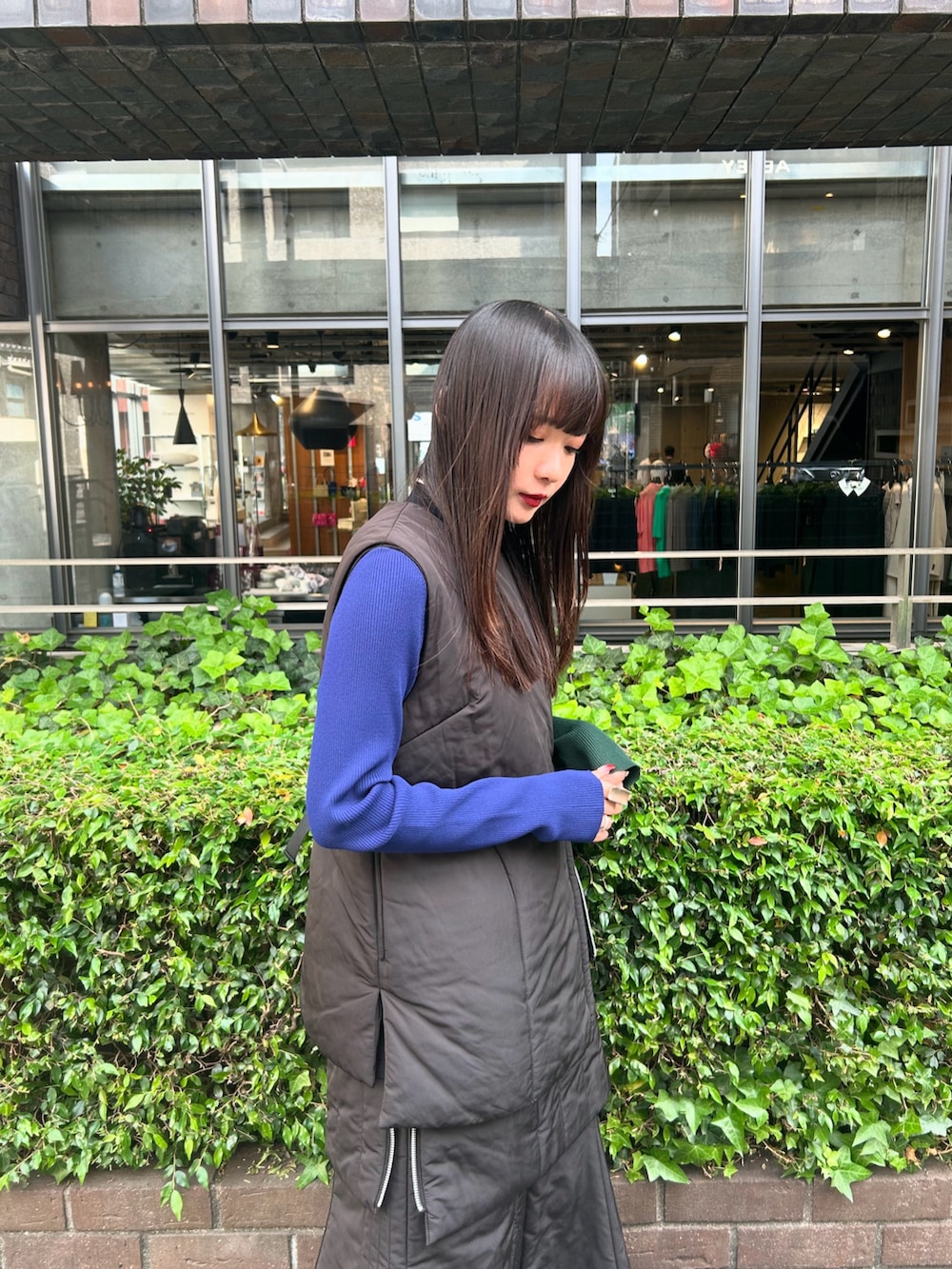 ブラック系のニット/セーター、ブラック系のスカート、ブラック系のダウンベストを着用したレディースの夏コーディネートの2枚目の写真