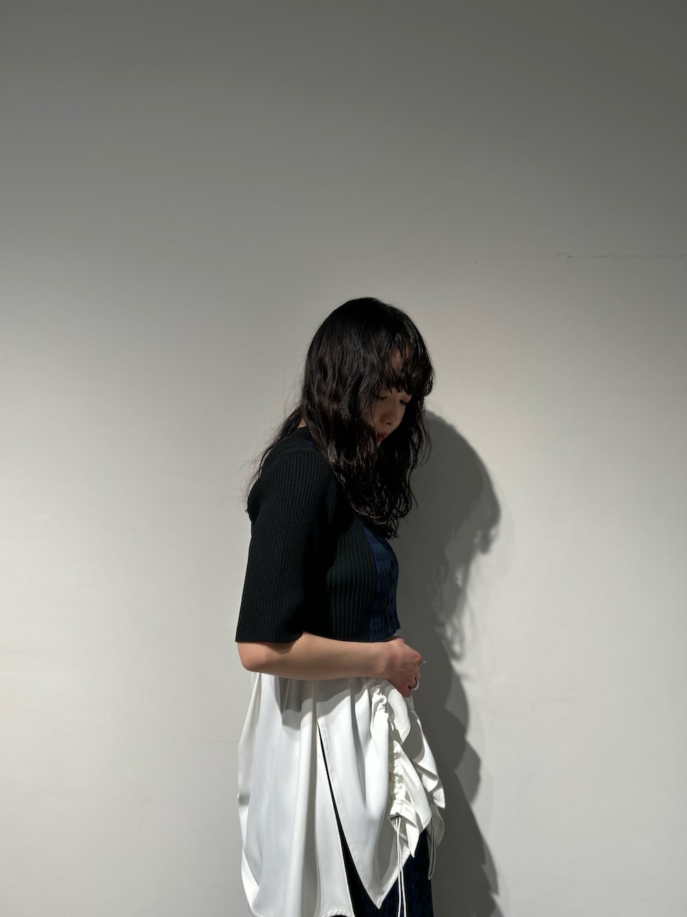 シルバー系のブーツ、ブラック系のスカート、ホワイト系のタンクトップを着用したレディースの冬コーディネートの3枚目の写真