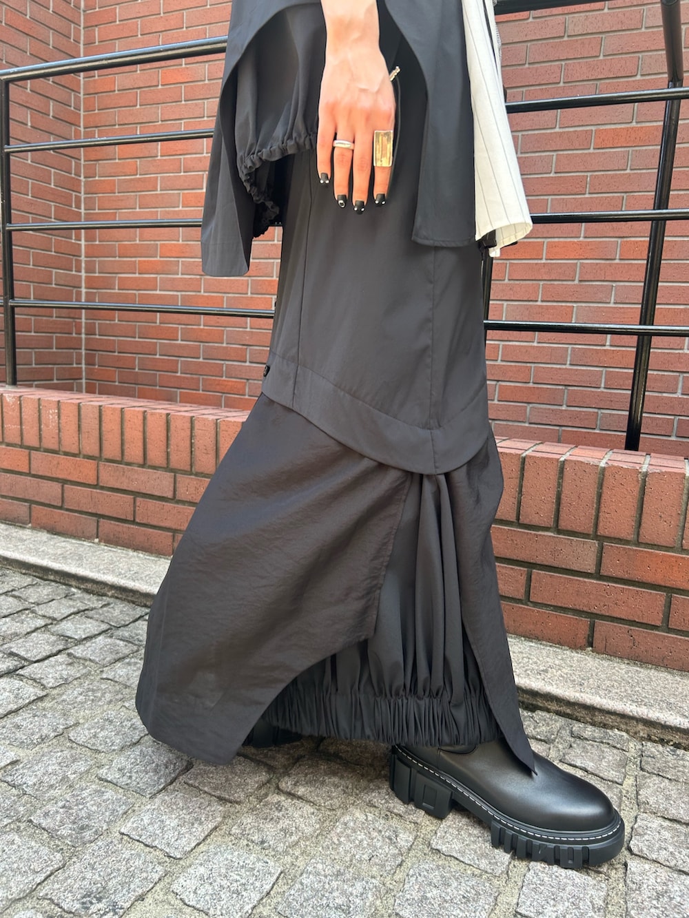 ブラック系のスカート、ブラック系のTシャツ/カットソー、ブラック系のブーツを着用したレディースの夏コーディネートの8枚目の写真