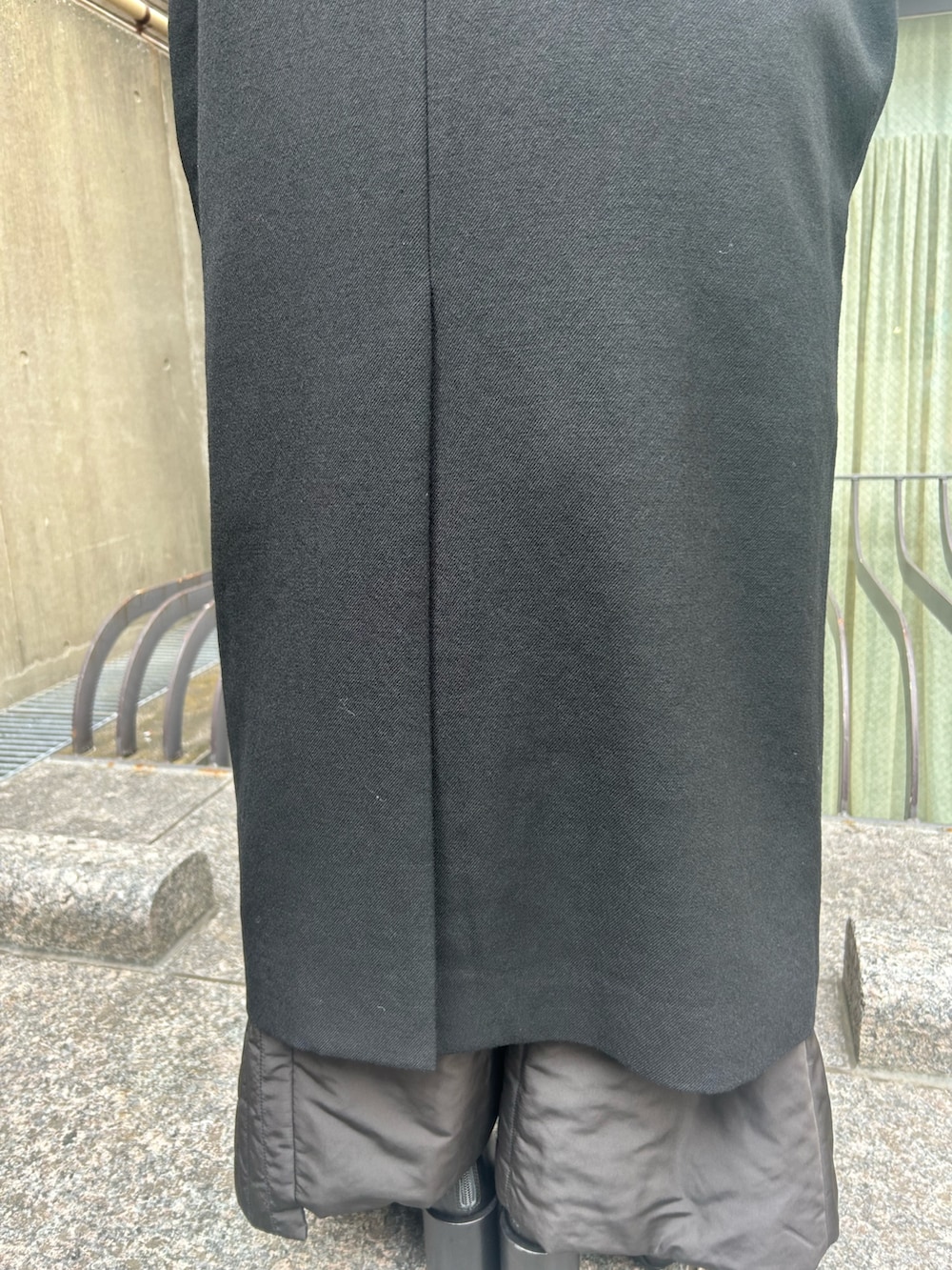 ブラック系のステンカラーコート、ブラック系のブーツを着用したレディースの秋コーディネートの7枚目の写真