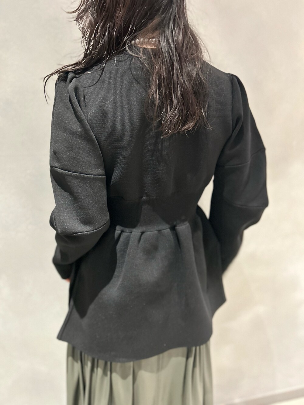 ブラック系のカーディガン/ボレロ、グリーン系のスカート、ブラック系のブーツを着用したレディースの秋コーディネートの5枚目の写真