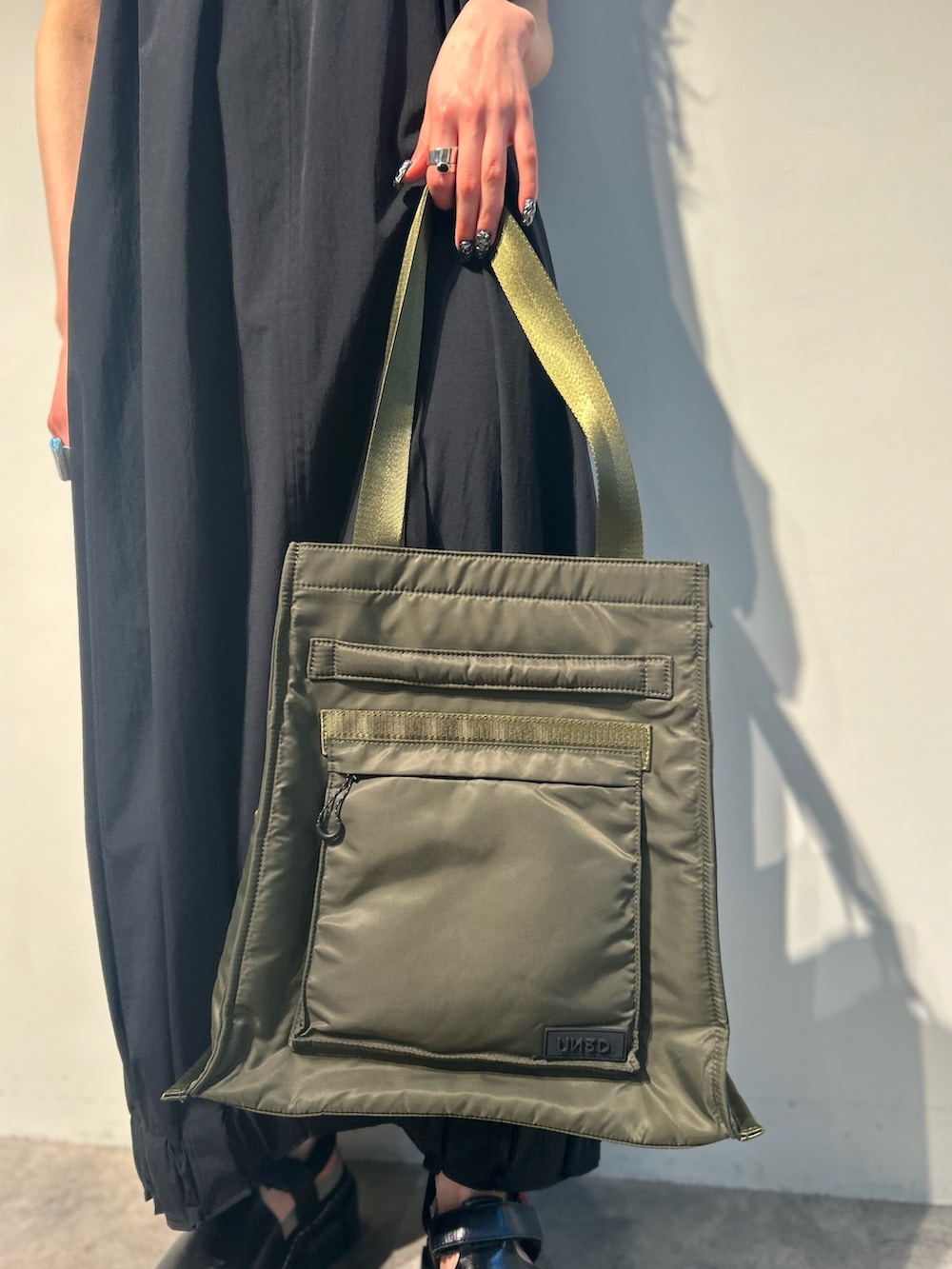 ブラック系のワンピース、グリーン系のトートバッグ、その他のサンダルを着用したレディースの夏コーディネートの8枚目の写真