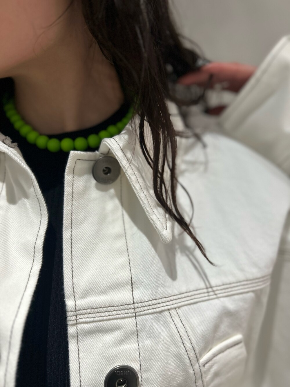 ホワイト系のデニムパンツ、ホワイト系のデニムジャケット、ブラック系のニット/セーターを着用したレディースの春コーディネートの6枚目の写真