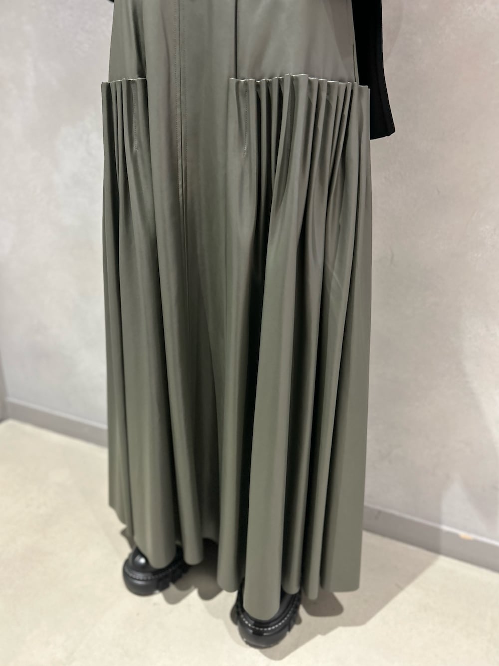 ブラック系のカーディガン/ボレロ、グリーン系のスカート、ブラック系のブーツを着用したレディースの秋コーディネートの9枚目の写真