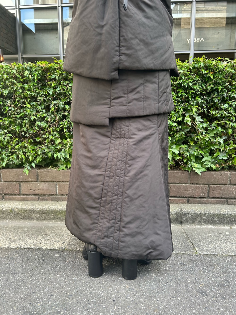 ブラック系のニット/セーター、ブラック系のスカート、ブラック系のダウンベストを着用したレディースの夏コーディネートの8枚目の写真