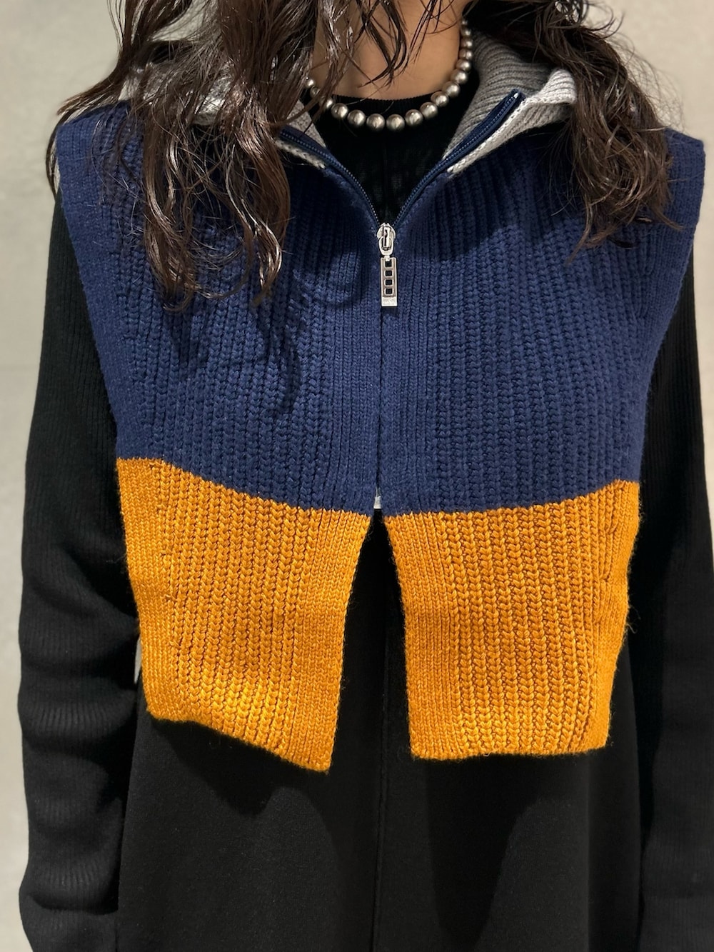 ブラック系のワンピース、ブラック系のブーツ、グレー系のネックウォーマー/スヌードを着用したレディースの冬コーディネートの5枚目の写真